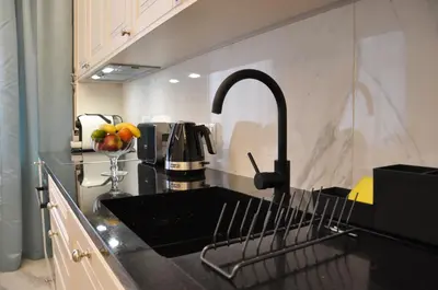 a kitchen with a sink with a dish drying rack at Tresor Barska Apartments in Kraków