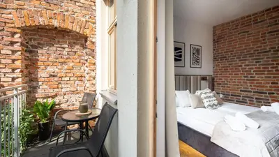 a bedroom with a bed and a balcony with a brick wall at Aparthotel Delta Boutique in Kraków