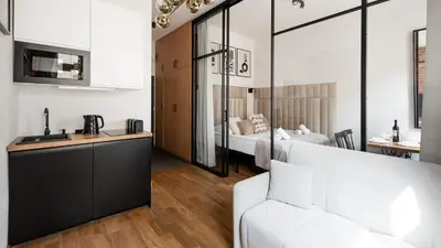 a living room with a white couch and a bedroom at Aparthotel Delta Boutique in Kraków