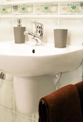 a white bathroom sink with two cups on it at D&A Apartments Szewska in Kraków
