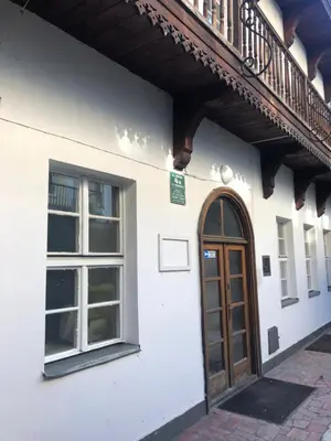 a white building with a wooden door and a balcony at D&A Apartments Szewska in Kraków