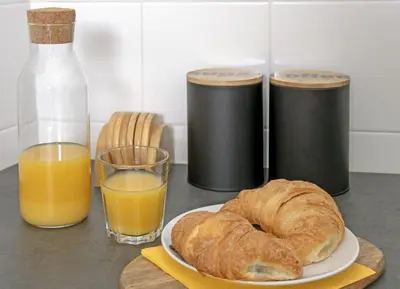 a table with a plate of bread and a glass of orange juice at 3D FLORIANSKA 15 Apartament in Kraków