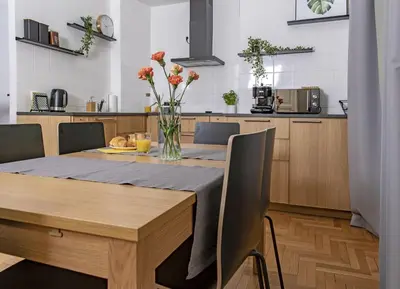 a kitchen with a wooden table with a vase of flowers at 3D FLORIANSKA 15 Apartament in Kraków