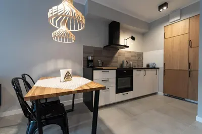 a kitchen with a wooden table and a counter top at City Lights Rakowicka 15 in Kraków
