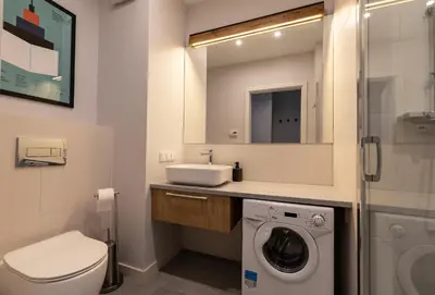 a bathroom with a washing machine and a sink at City Lights Rakowicka 15 in Kraków