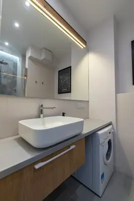 a bathroom with a sink and a washing machine at City Lights Rakowicka 15 in Kraków