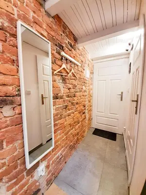 a brick hallway with a mirror and a white door at LION apartments in Kraków