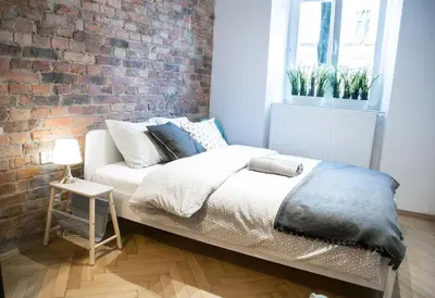 a bed in a room with a brick wall at LION apartments in Kraków