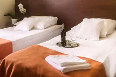 two beds with towels and a bottle and glasses on them at Vinci Hotel Airport in Modlniczka