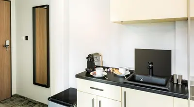 a kitchen with white cabinets and a black counter top at Camera Apartments in Kraków