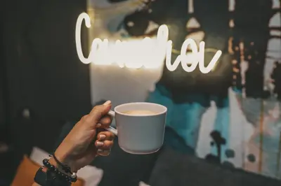 a person holding up a cup of coffee at Camera Apartments in Kraków