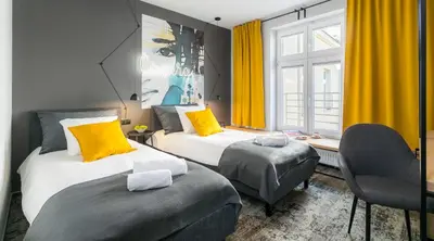 two beds in a room with yellow curtains at Camera Apartments in Kraków