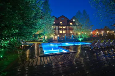 a swimming pool at night with chairs and a building at Hotel&SPA Jawor in Zawoja
