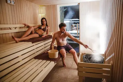 a man and a woman sitting in a sauna at Hotel&SPA Jawor in Zawoja