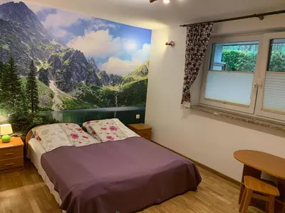 a bedroom with a bed with a mountain mural on the wall at Domek pod Maciejową in Rabka