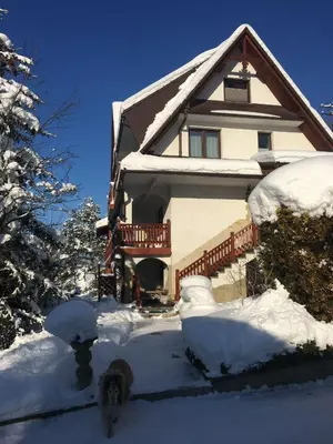 a house with snow on the front of it at Domek pod Maciejową in Rabka