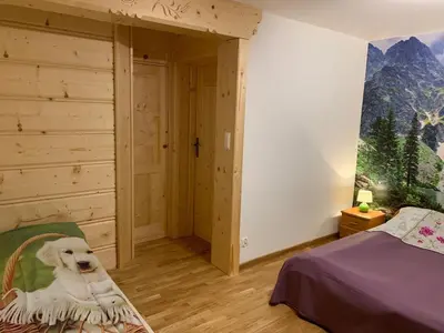 a white dog sitting on a bed in a bedroom at Domek pod Maciejową in Rabka