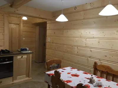 a dining room with a table and a wooden wall at Domek pod Maciejową in Rabka