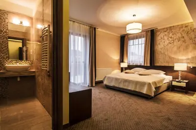 a bedroom with a bed and a bathroom with a sink at Hotel Tatarscy - ENERGYLANDIA in Kalwaria Zebrzydowska