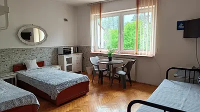 a bedroom with two beds and a table and a window at Pokoje Gościnne U Ewy in Wieliczka