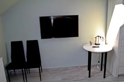 a room with two chairs and a table and a tv on the wall at Motel Lunar in Oświęcim
