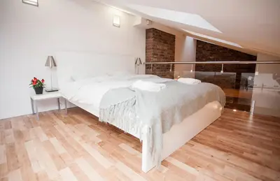 a white bedroom with a large bed and a wooden floor at Rainbow Apartments 1 in Kraków
