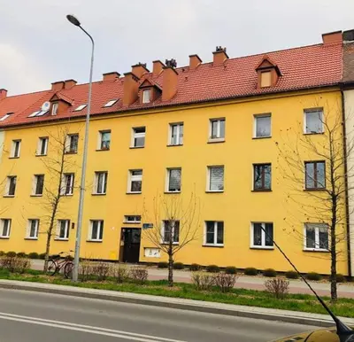a large yellow building with a red roof at Apartament Bernadett in Oświęcim