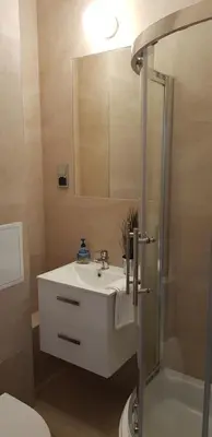 a bathroom with a white sink and a shower at Apartament Bernadett in Oświęcim