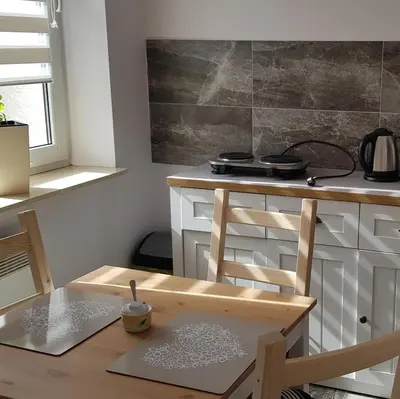 a kitchen with a wooden table and a wooden chair at Apartament Bernadett in Oświęcim