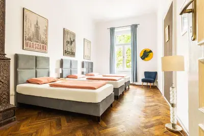 three beds in a room with wooden floors at Das Hostel in Kraków