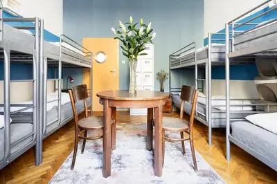 a room with a table and chairs and bunk beds at Das Hostel in Kraków