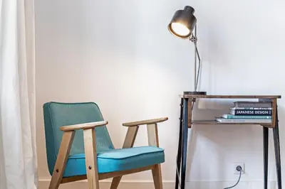 a chair next to a desk with a lamp at Relaks Apartamenty in Kraków