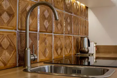 a sink in a kitchen with a wooden wall at Relaks Apartamenty in Kraków