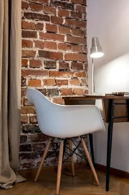 a white chair next to a desk with a brick wall at Relaks Apartamenty in Kraków