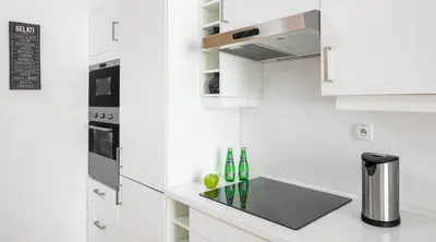 a kitchen with white cabinets and a counter with bottles at City View Apartments in Kraków