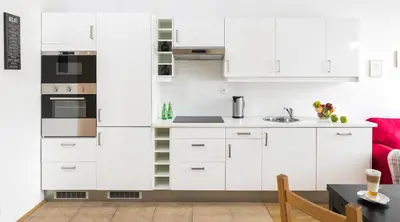a kitchen with white cabinets and a red couch at City View Apartments in Kraków