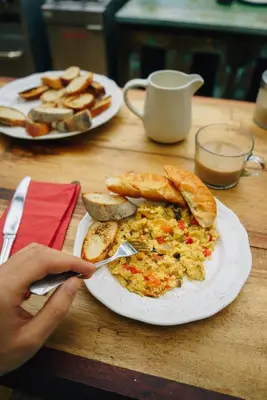 a person eating a breakfast of eggs and bread on a table at City View Apartments in Kraków