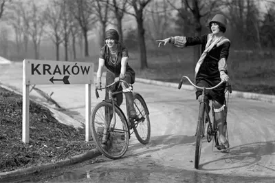 two people riding bikes on a road next to a sign at Tweety Cracow House in the Old Town in Kraków
