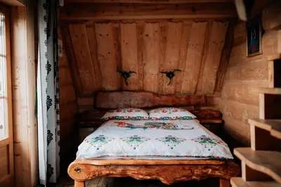 a bed in a room with a wooden wall at Jarogówka Stylowy dom góralski in Obidowa