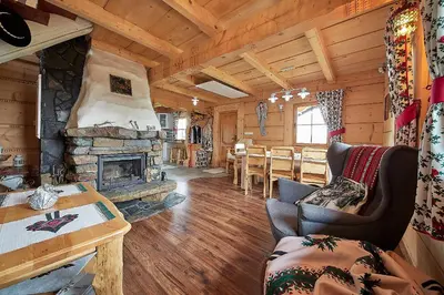 a living room with a fireplace in a log cabin at Jarogówka Stylowy dom góralski in Obidowa