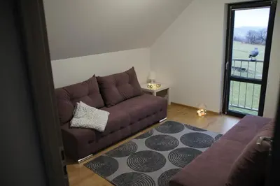 a living room with a brown couch and a rug at Domek Tadeusz in Śleszowice Górne
