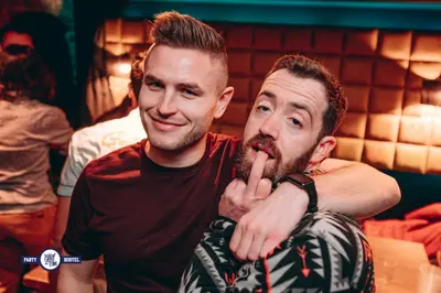 two men sitting next to each other with their finger in their mouth at Greg&Tom Party Hostel in Kraków