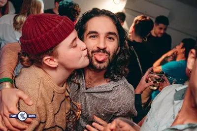 a woman kissing a man in a crowd of people at Greg&Tom Party Hostel in Kraków