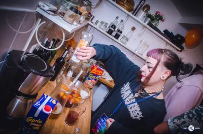 a woman is making a drink in a kitchen at Greg&Tom Party Hostel in Kraków