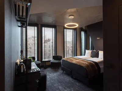 a bedroom with a bed and a chair and windows at The Loft Hotel Adults Only in Kraków
