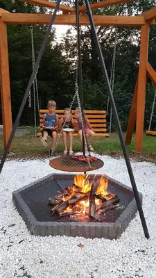 two children sitting on a swing over a fire at Domki Pod Jałowcem in Lachowice