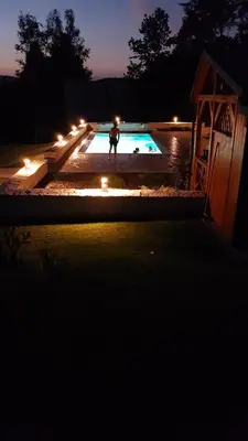 a person standing in front of a swimming pool at night at Domki Pod Jałowcem in Lachowice