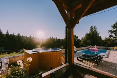 a hot tub on a patio next to a pool at Domki Pod Jałowcem in Lachowice