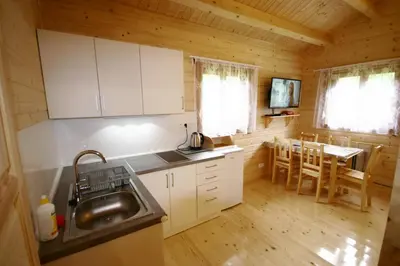 a kitchen with white cabinets and a sink and a table at Domki Pod Jałowcem in Lachowice