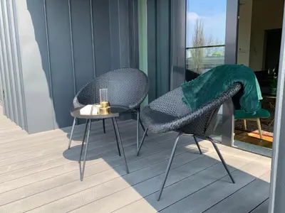 two chairs and a side table on a balcony at AGIHOME Rajska 3 Apartments in Kraków